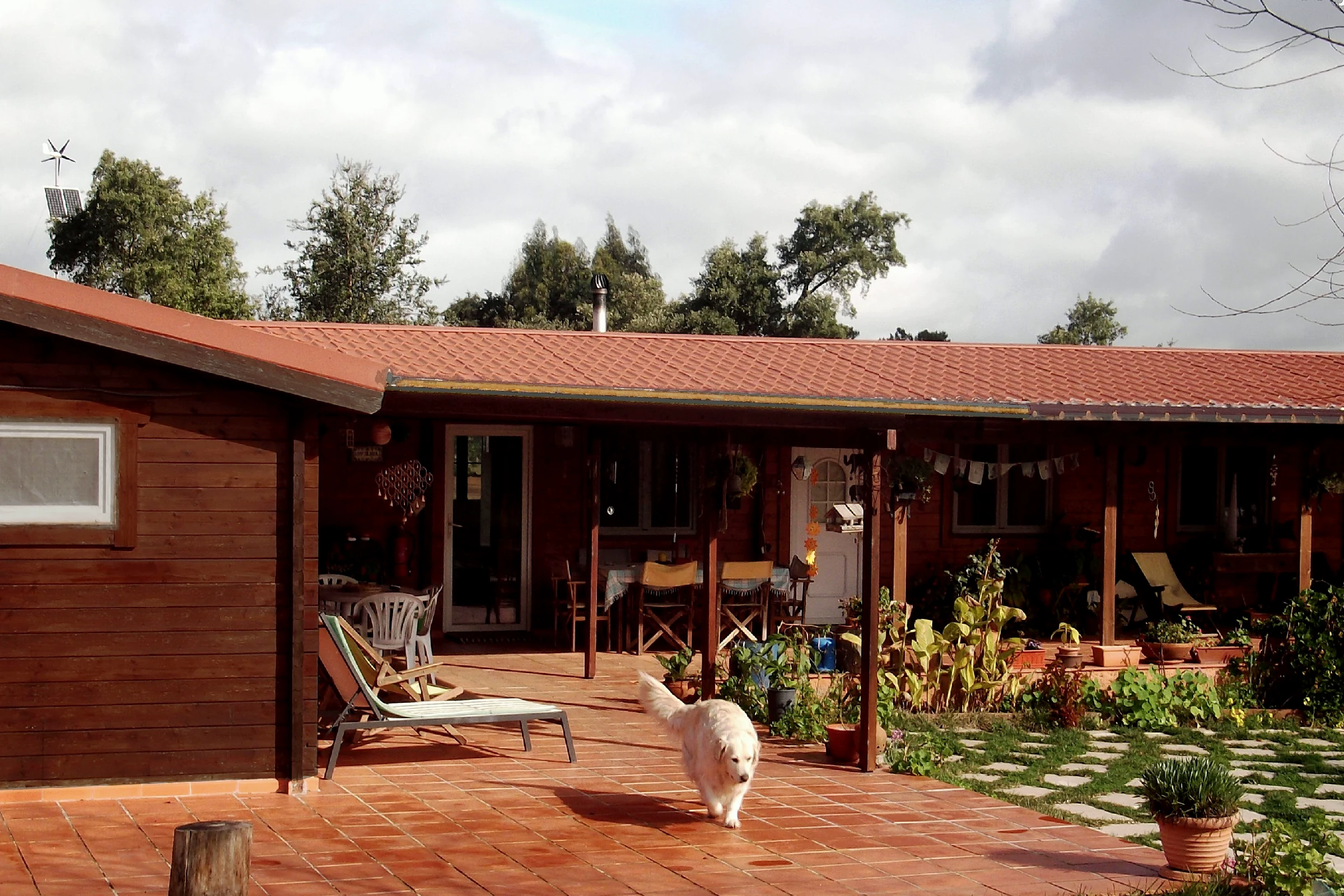 A real, lived-in VeredaoSol timber home years after construction, with a weathered façade, planted terrace and everyday life around it.